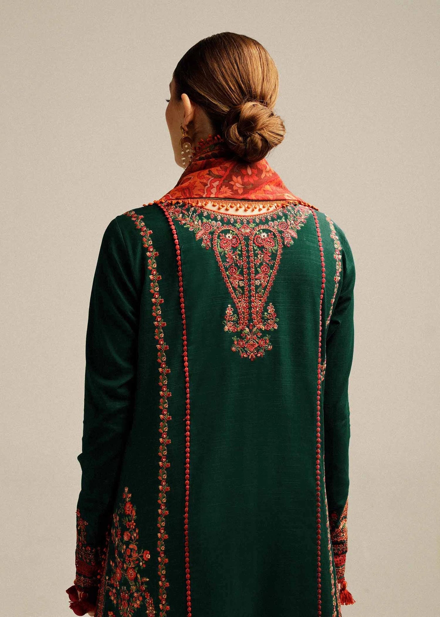 Green embroidered garment with a red and gold pattern on a plain background