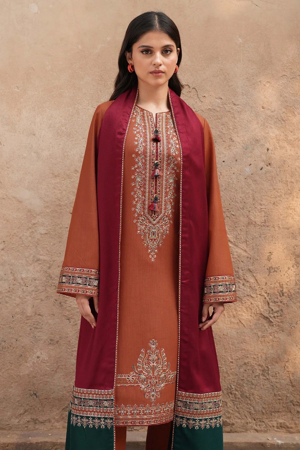 Woman wearing a traditional outfit with maroon and orange embroidery